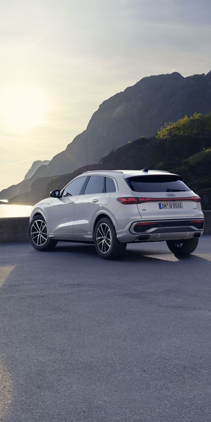 Ein weißer Q5 SUV e-hybrid steht auf einem Parkplatz an der Küste.