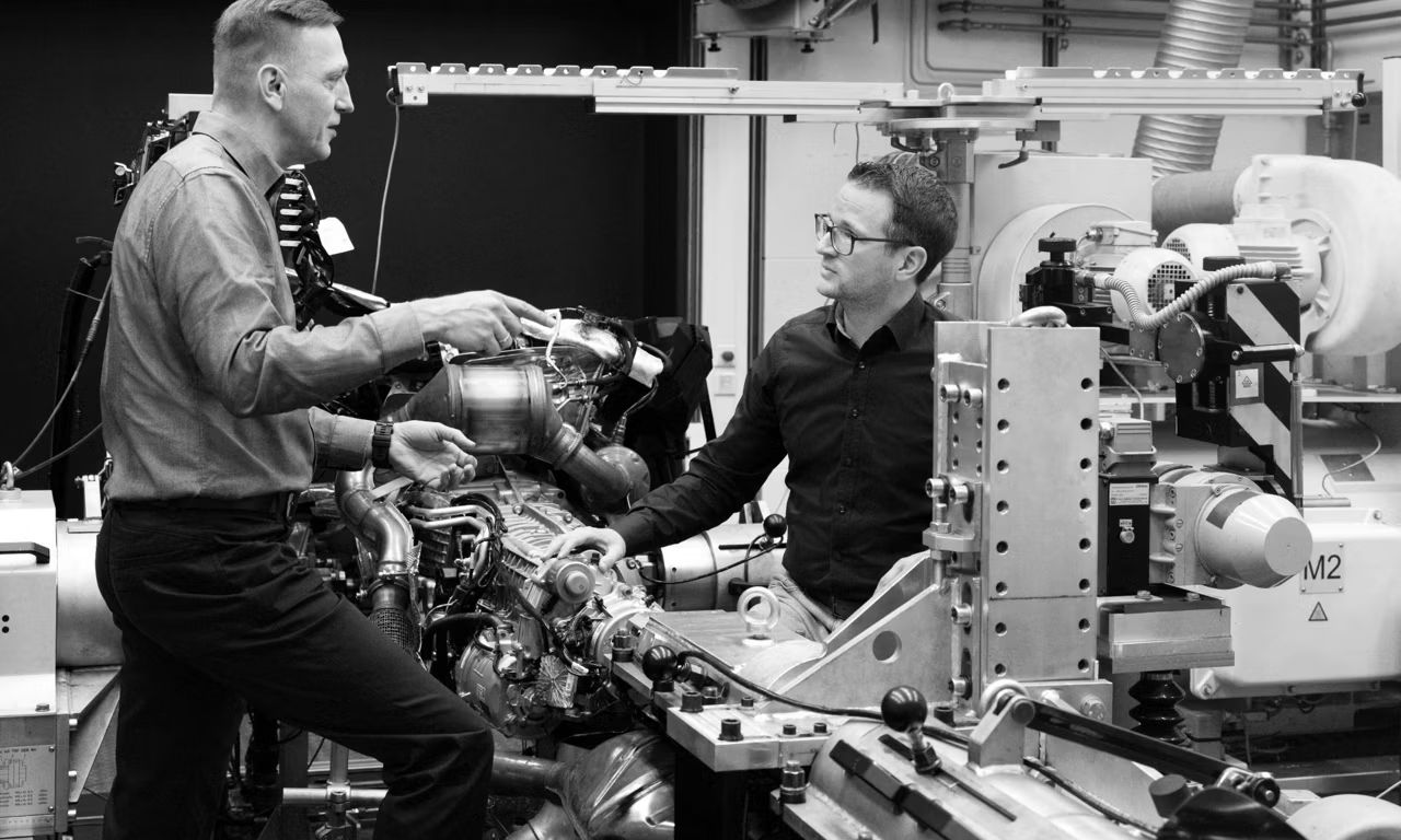 Dvaja muži v skúšobni diskutujú pri skúšobnej stolici. Okolo nich sú rôzne zariadenia.