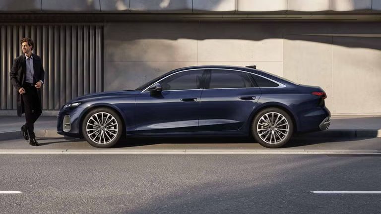 Audi A6 Limuzína na parkovacom mieste pred budovou. Pred vozidlom stojí mladý muž