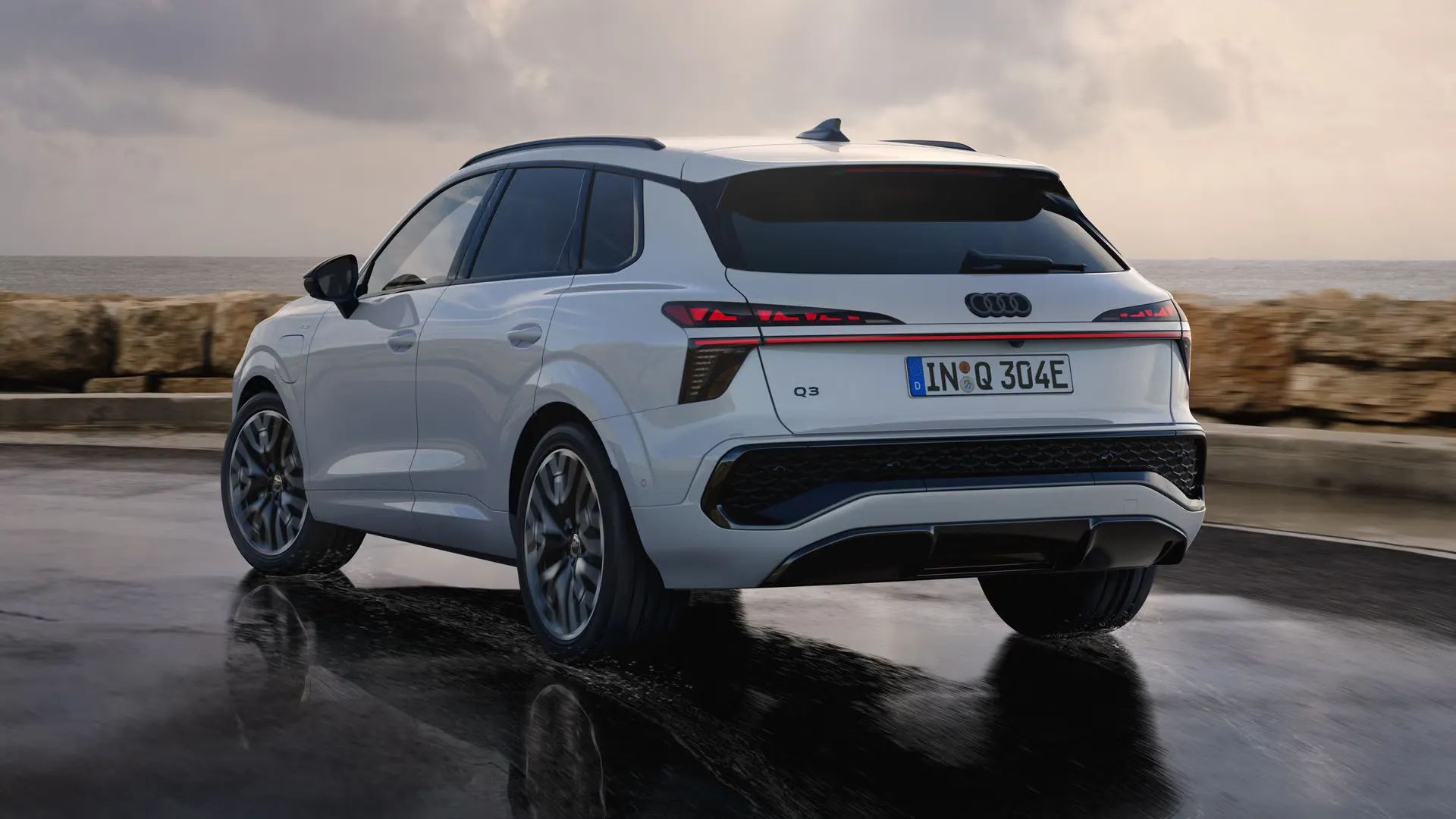 Audi Q3 e-hybrid na mokrej ceste pri pobreží.