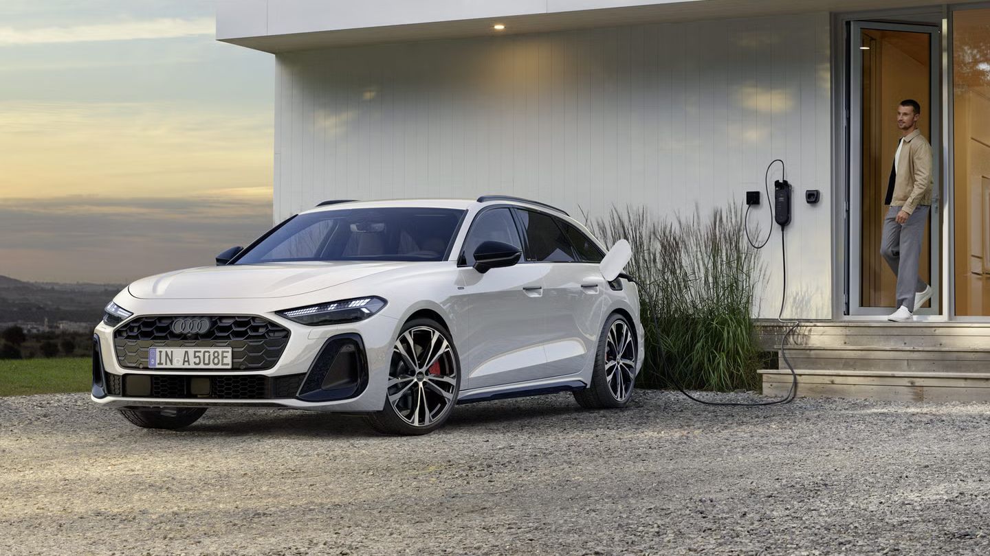 Ein weißer Audi A5 Avant e-hybrid lädt an einer heimischen Wallbox
