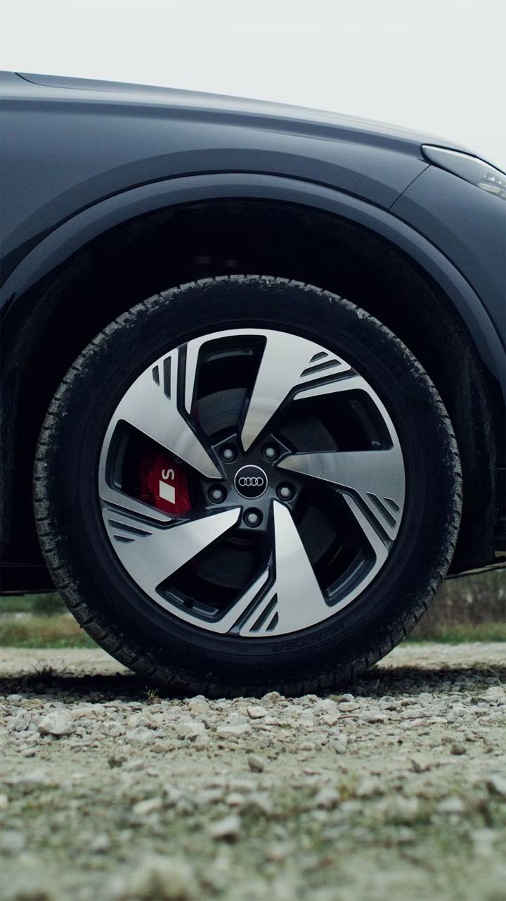 Detail na koleso s moderným čierno-strieborným diskom. Koleso stojí na štrkovom povrchu.