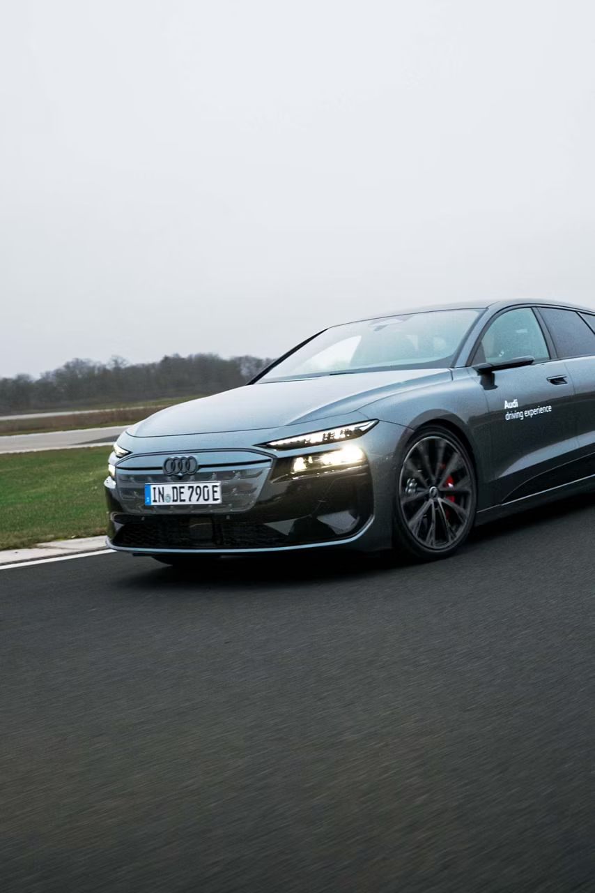 Audi S6 Avant e-tron na pretekárskom okruhu počas jazdy. V pozadí vidieť vysoké stromy.