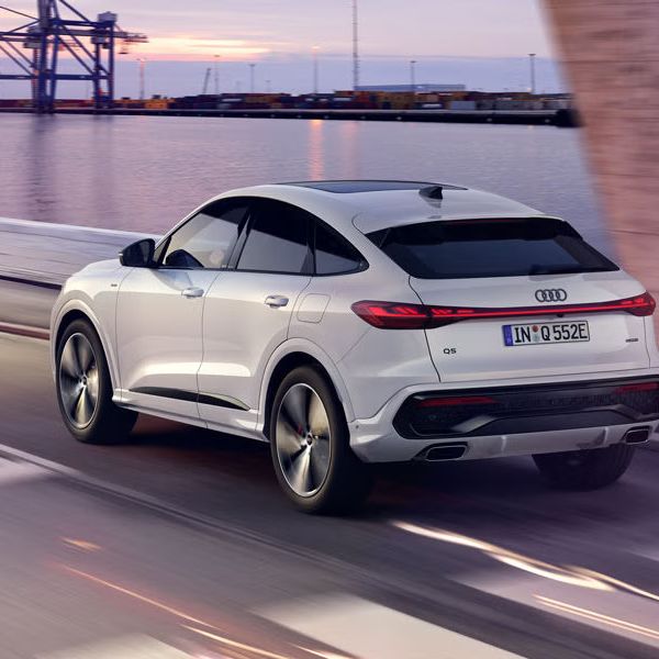 Pohľad na zadné partie Audi Q5 Sportback e-hybrid počas dynamickej jazdy popri pobreží.
