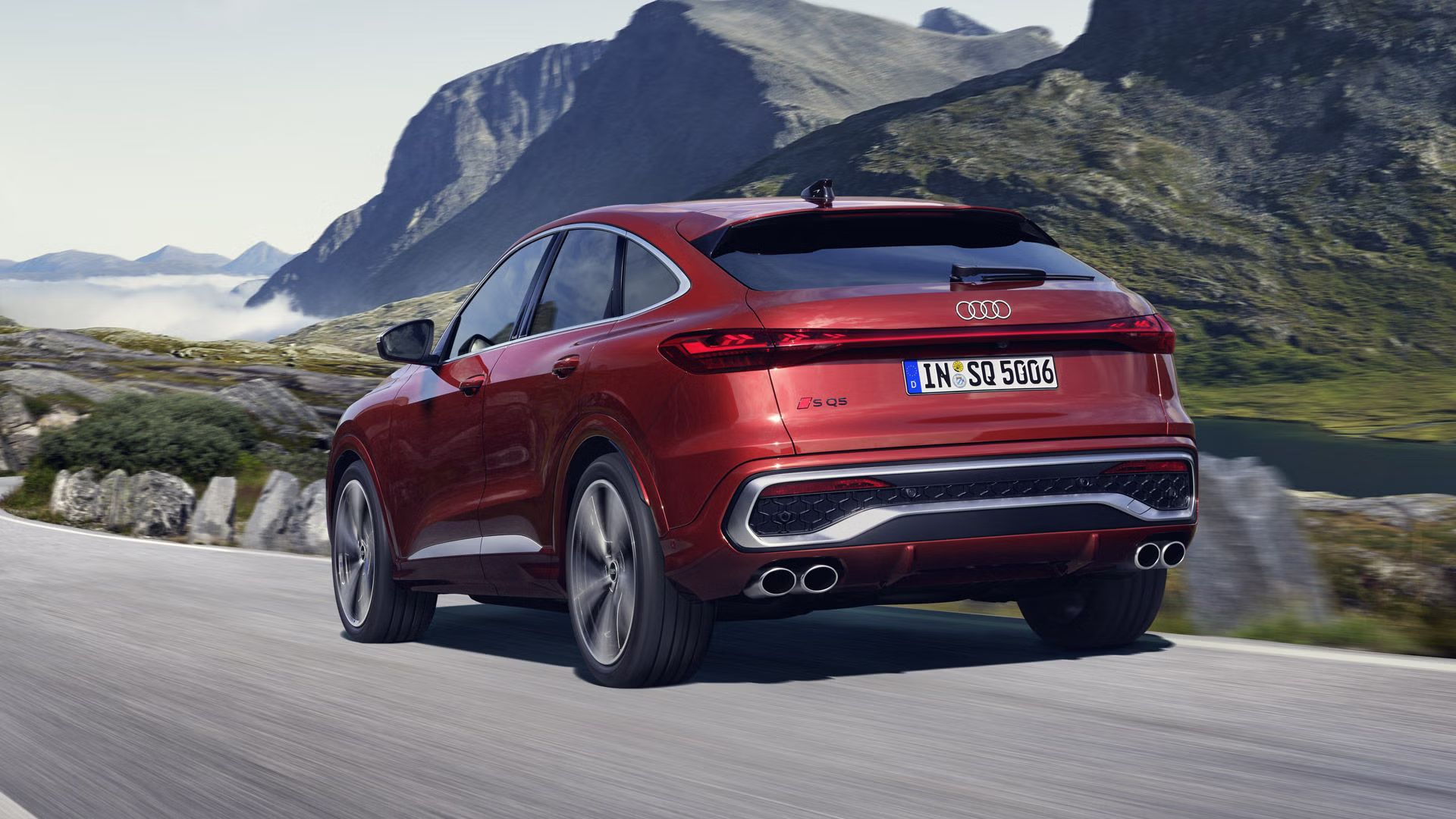Pohľad na zadné partie modelu Audi SQ5 Sportback počas dynamickej jazdy na ceste v horách.