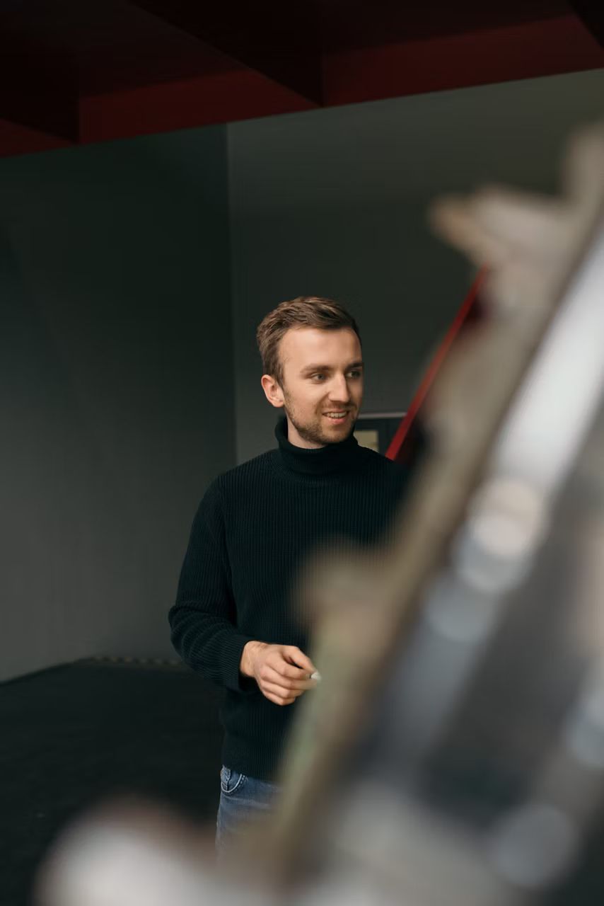 Mladý  už v čiernom roláku v kancelárii. 