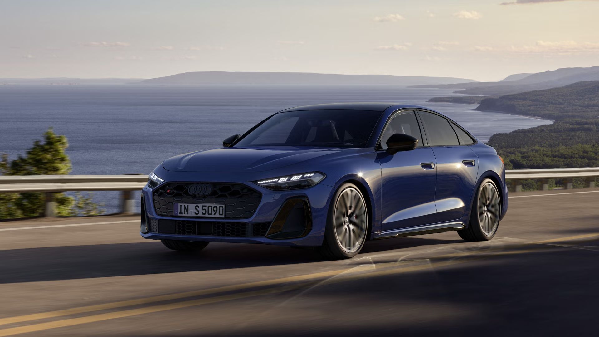 Pohľad spredu na modré Audi S5 Limuzína počas jazdy popri pobreží.