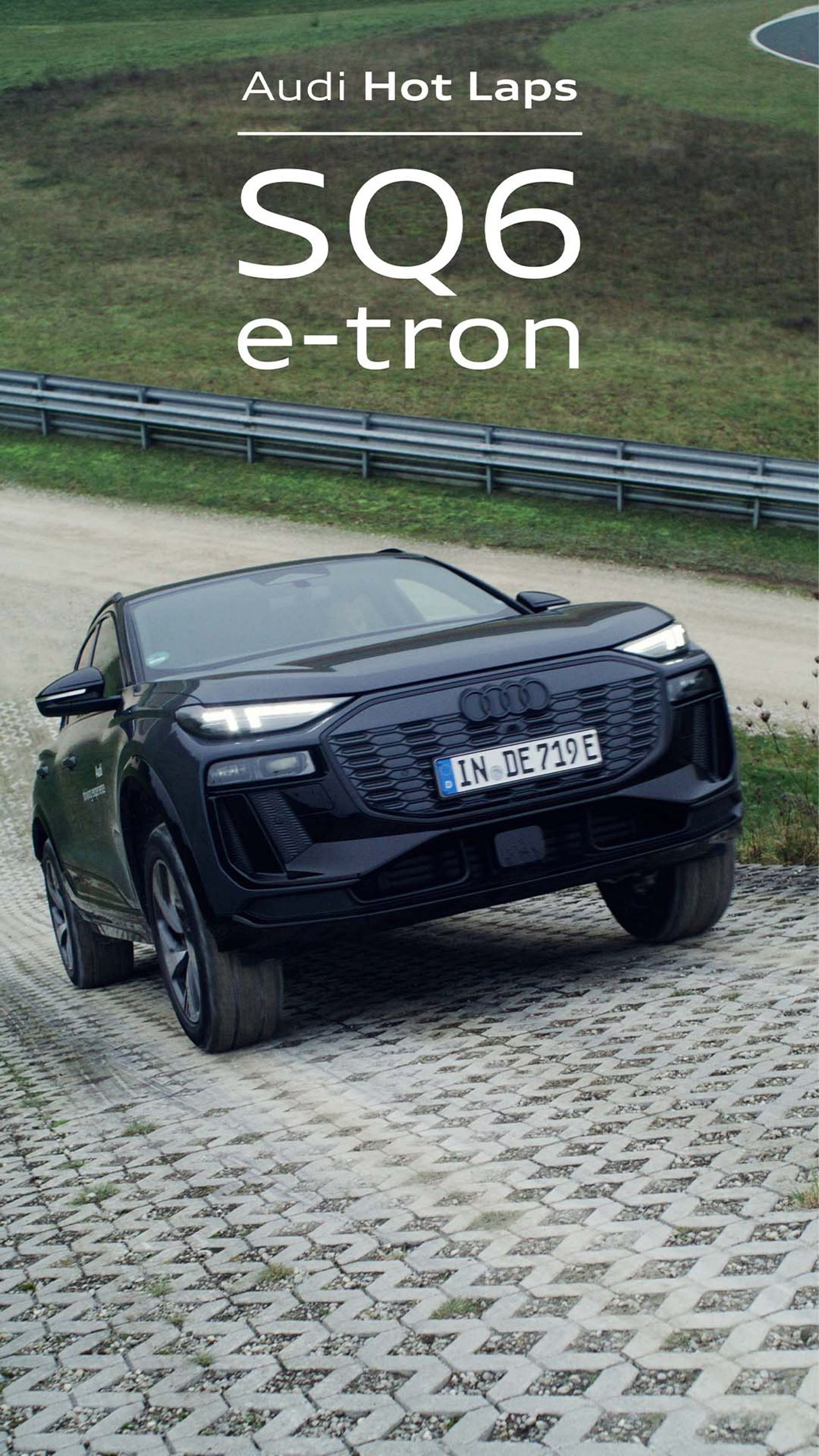Audi SQ e-tron pri stúpaní do strmého kopca. V pozadí je nespevnená cesta so zvodidlami, za nimi trávnatá plocha.