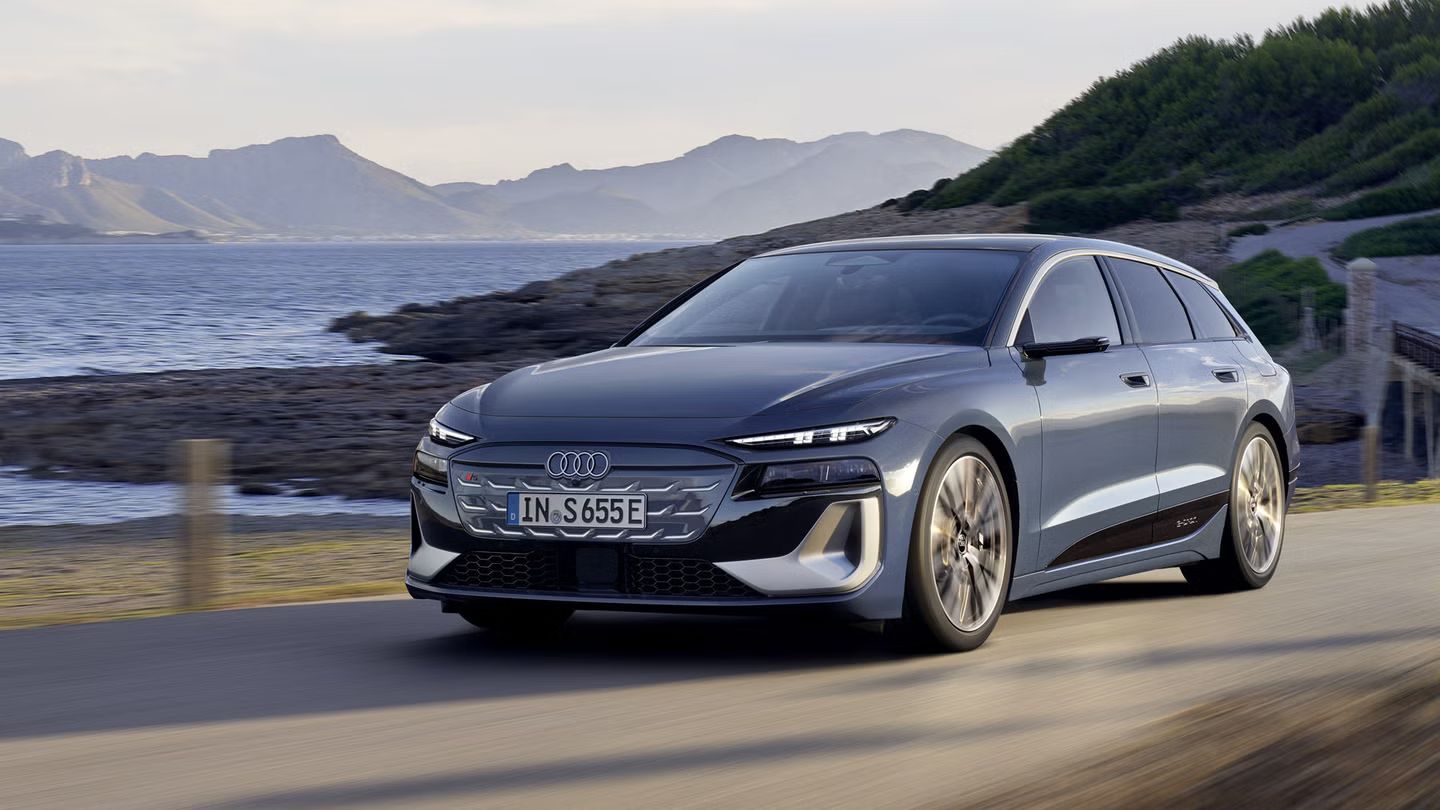 Audi S6 Avant e-tron z bočného pohľadu, ako jazdí po ceste popri pobreží. V pozadí sú vidieť hory. 