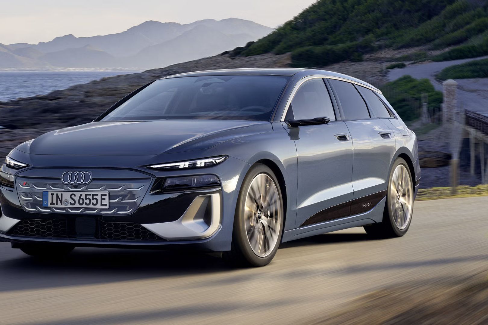 S6 Avant e-tron z bočného pohľadu počas jazdy popri pobrežia. V pozadí vidieť hory. 