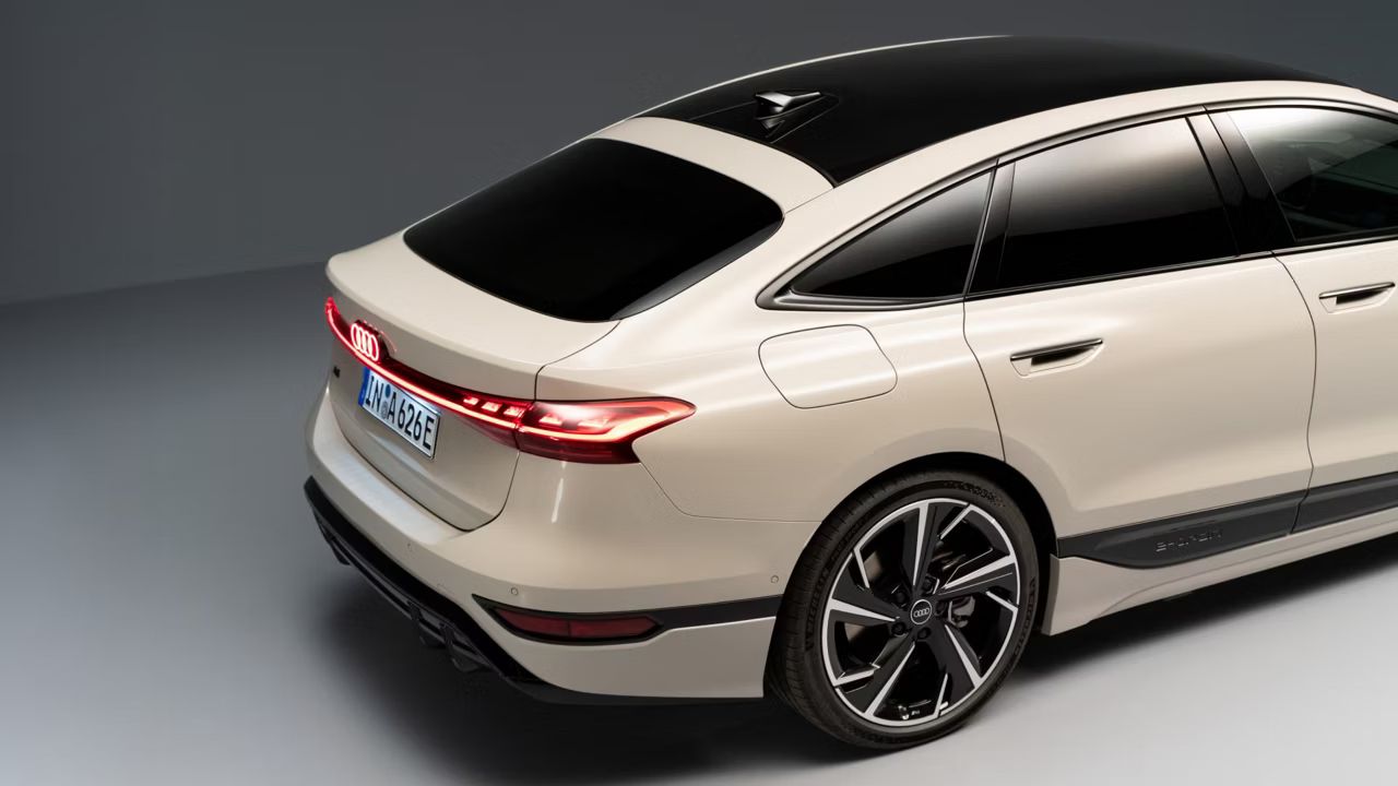 Pohľad na zadné partie zboku Audi A6 Sportback e-tron na sivej podlahe a pred sivou stenou.