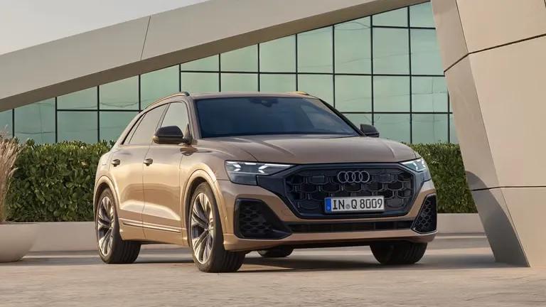 Audi Q8 SUV zaparkovaný šikmo z prednej strany stojí pred modernou budovou. 