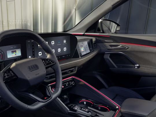 Pohľad na miesto vodiča v modeli SQ5 Sportback cez okno vodiča. Vidieť rôzne displeje prístrojového panela, ako aj červené ambientné osvetlenie.