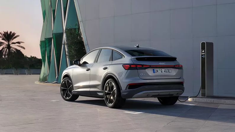 Audi Q4 e-tro zaparkované pri modernej verejnej budove a pripojené k verejnej nabíjacej stanici.