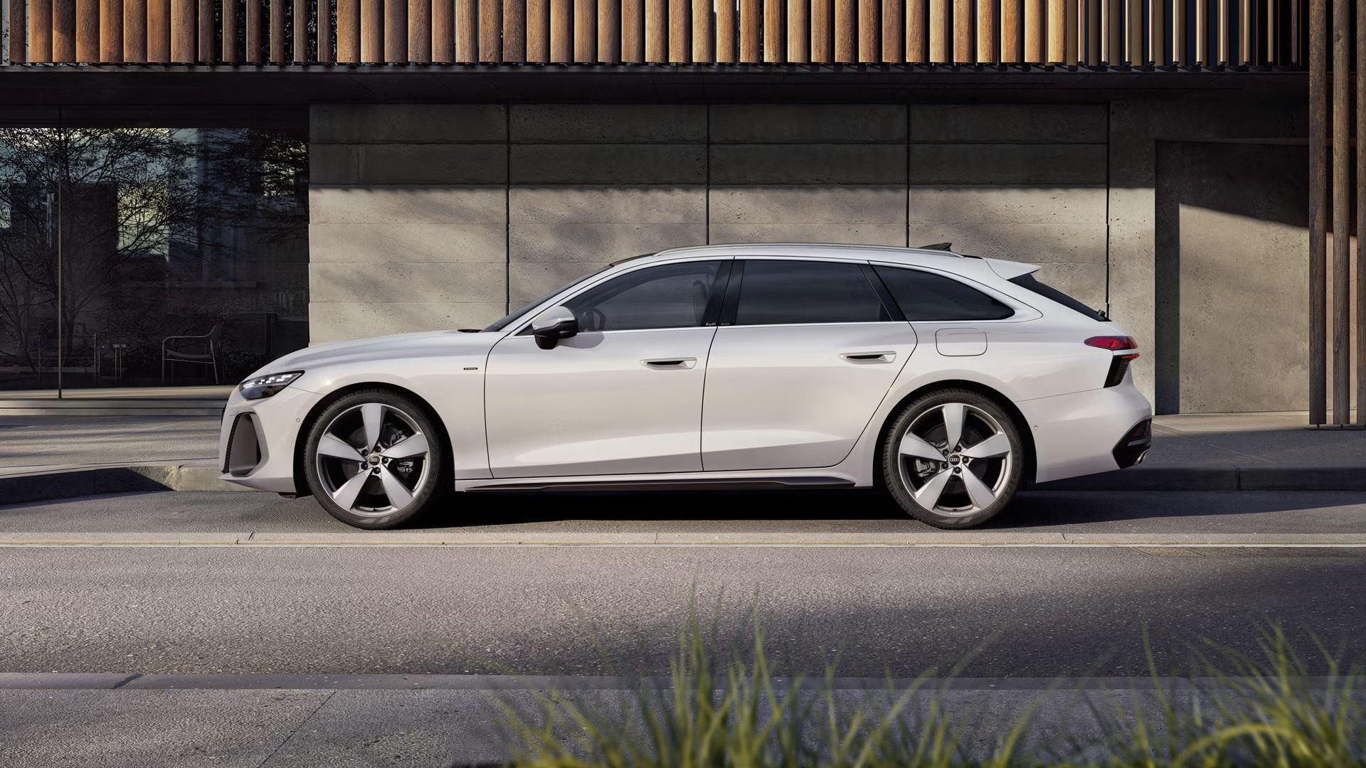 Audi A6 Avant e-hybrid stojí na parkovacom mieste pred budovou.