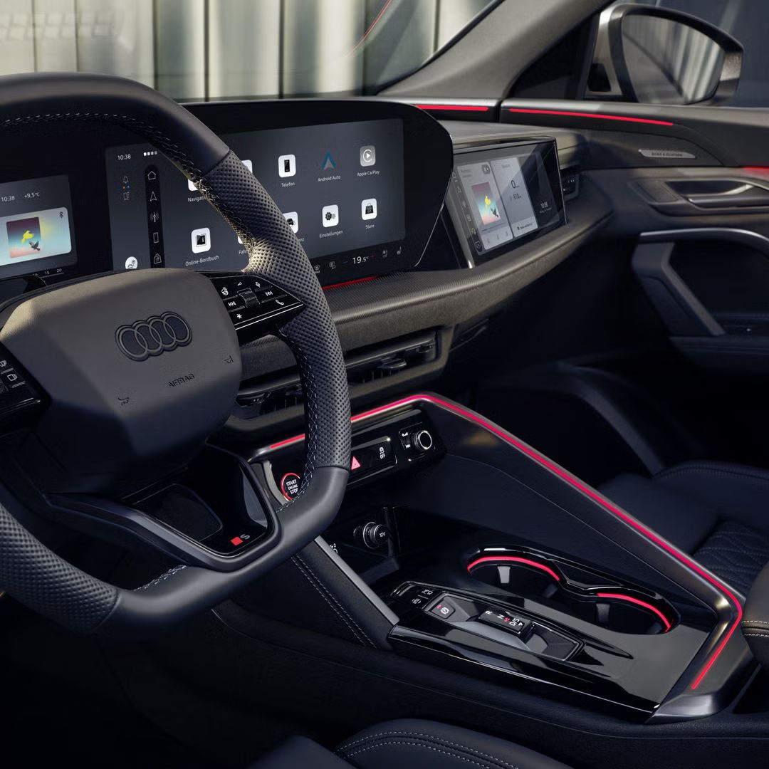 Pohľad na miesto vodiča v modeli SQ5 Sportback cez okno vodiča. Vidieť sú rôzne displeje Audi virtual cockpit, ako aj červené ambientné osvetlenie.