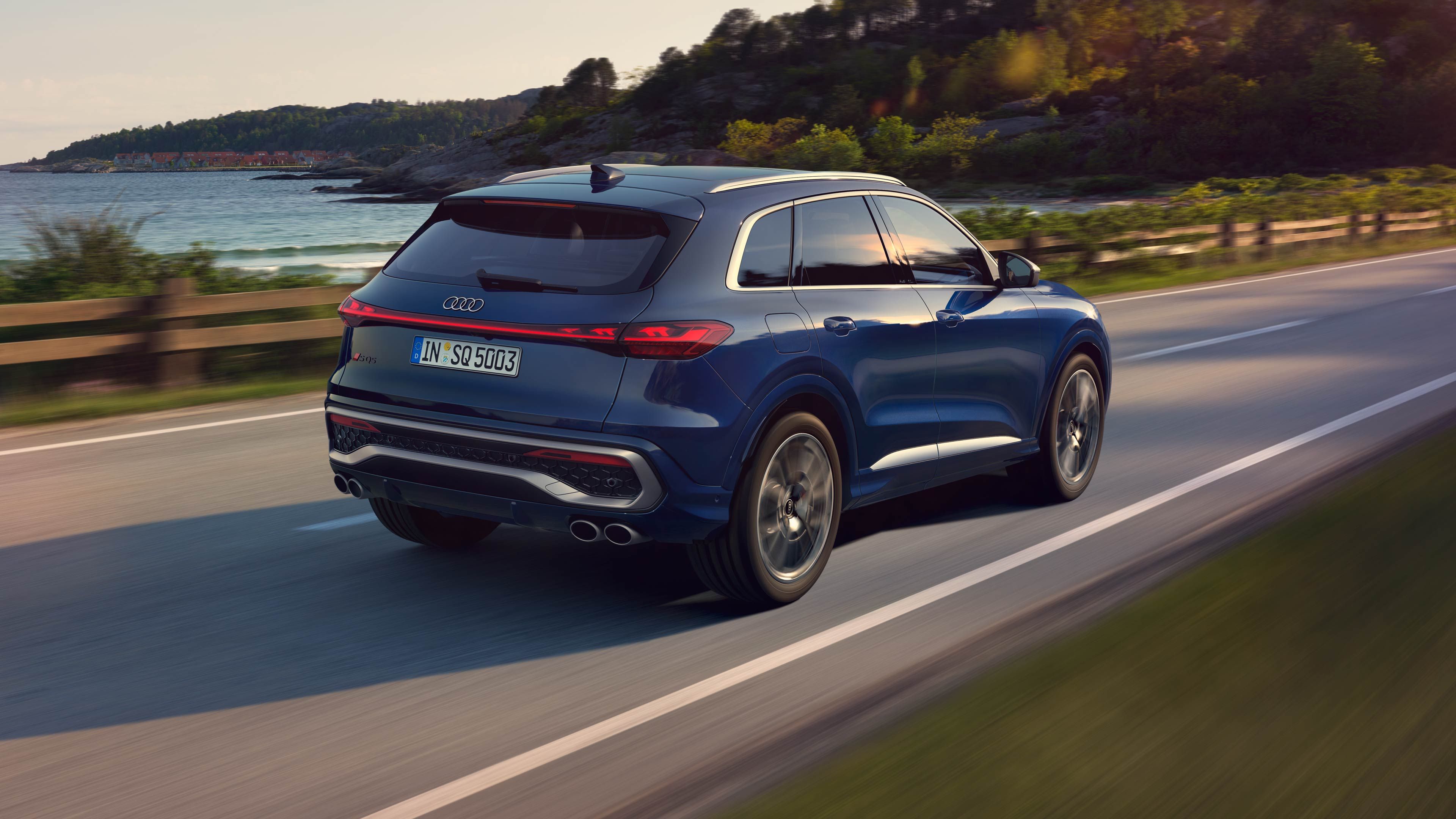 Bočný pohľad na zadné partie modrého Audi SQ5 SUV počas jazdy po ceste. 