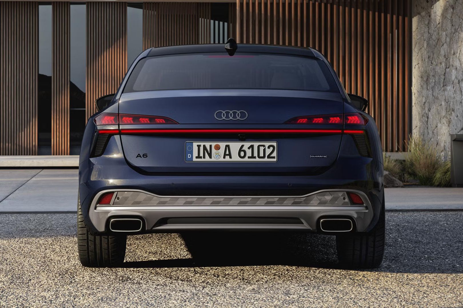 Pohľad na zadné partie modrého Audi A6 Limuzína, ktoré je zaparkované pred luxusnou vilou.