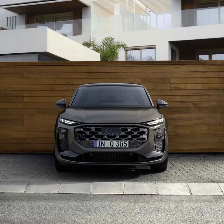 Audi Q3 Sportback stojí pred dreveným múrom moderného bytového domu.