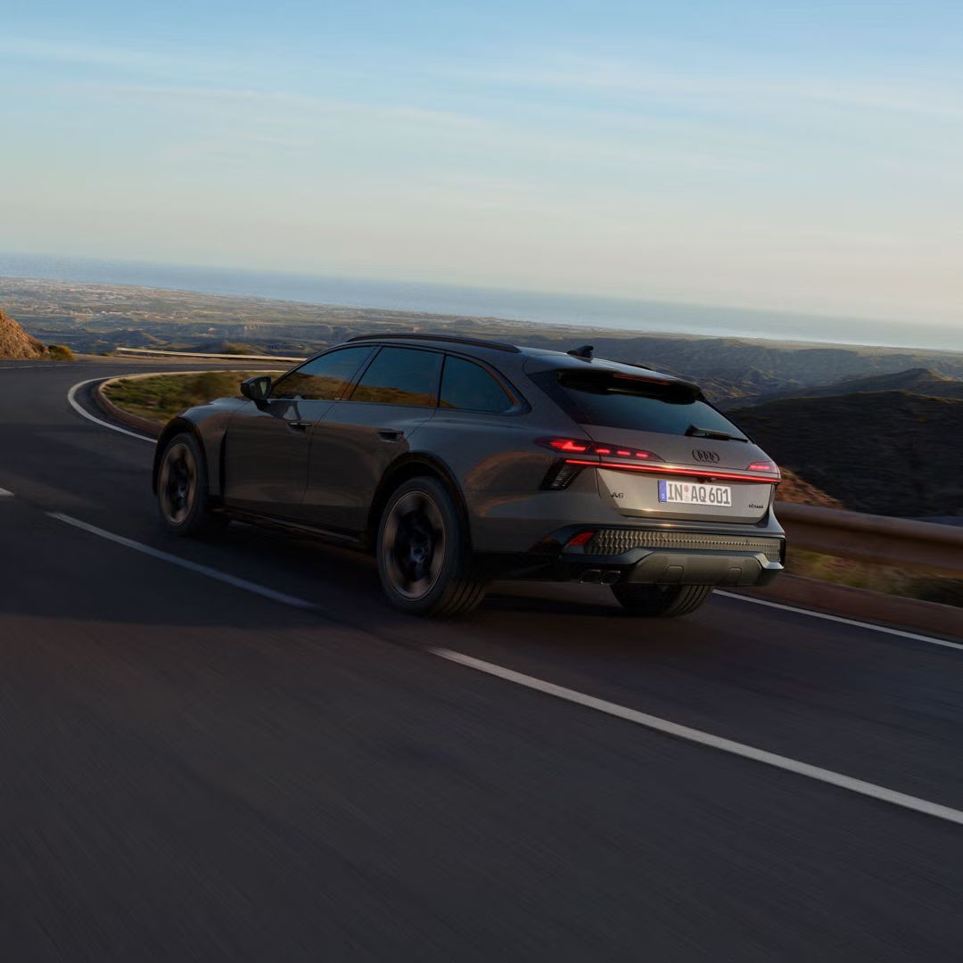 Audi A6 allroad zo šikmého uhla zozadu prechádza dlhou zákrutou.