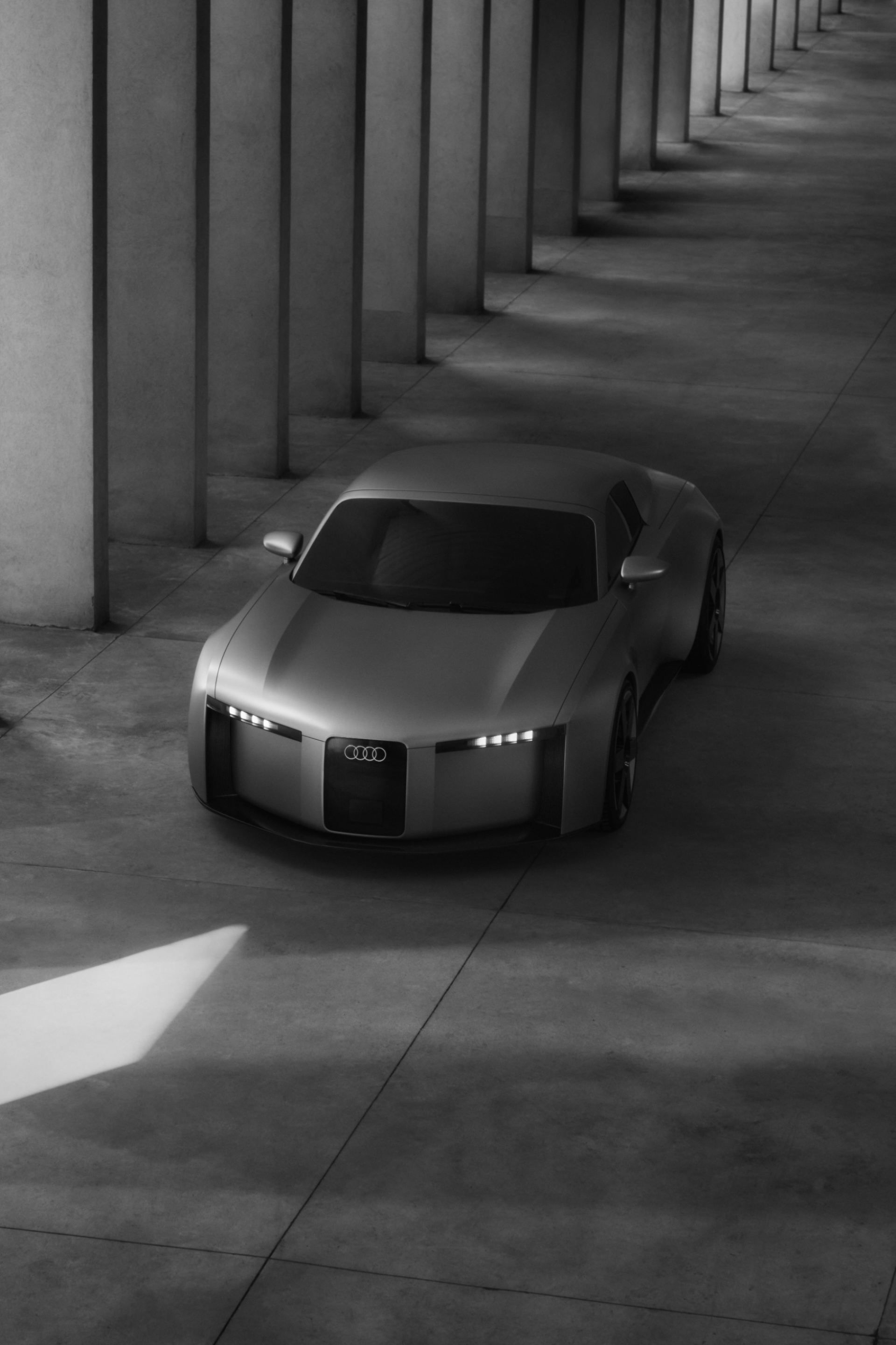 Audi Concept C na ceste okolo betónových stĺpov. Čiernobiele zobrazenie.