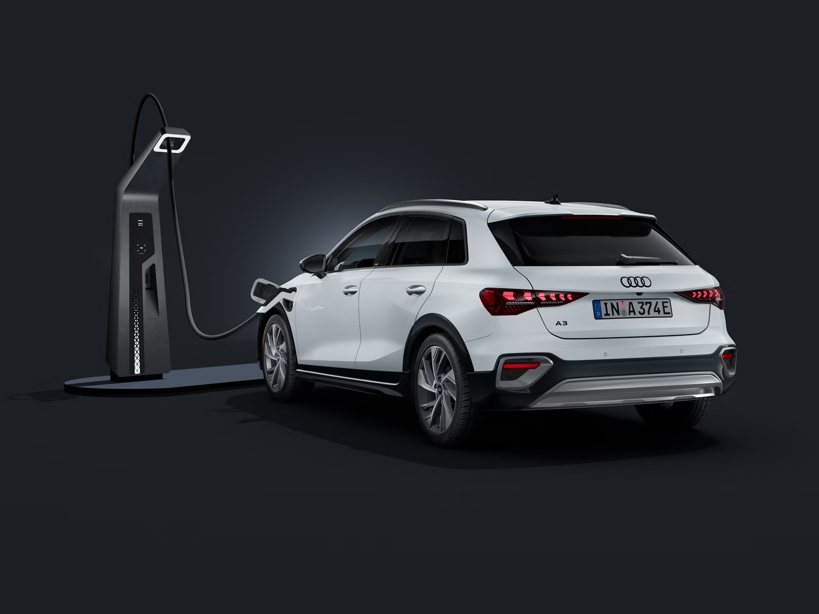 Audi A3 allstreet e-hybrid, zobrazené zozadu pod uhlom na tmavom pozadí, pripojené k modernej nabíjacej stanici.
