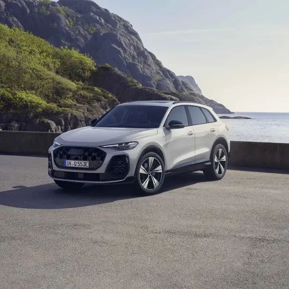 Audi Q5 SUV e-hybrid zaparkované na parkovisku na pobreží pri mori. V pozadí vidieť útesy.
