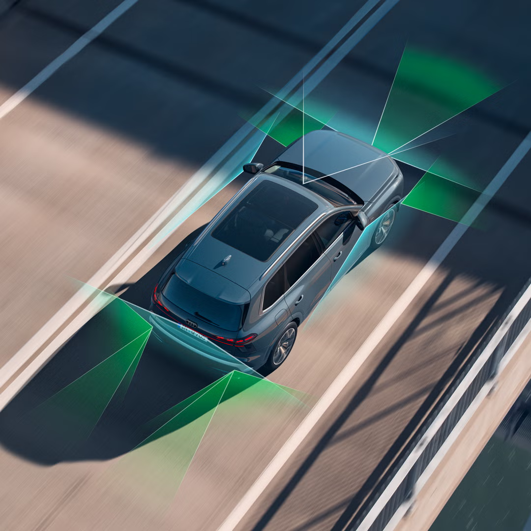 Audi Q7 SUV zo šikmého pohľadu zhora na ceste. Zelenými grafickými plochami je zobrazené fungovanie snímačov asistenčných systémov.