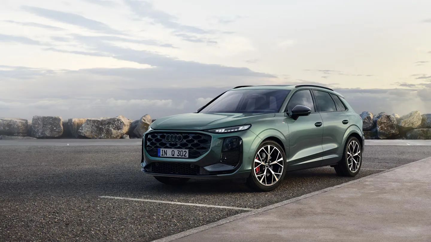 Zelené metalízové Audi Q3 SUV zaparkované na parkovisku pri pobreží.