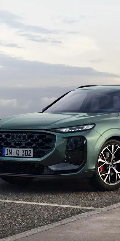 Zelené metalízové Audi Q3 SUV zaparkované na parkovisku pri pobreží.