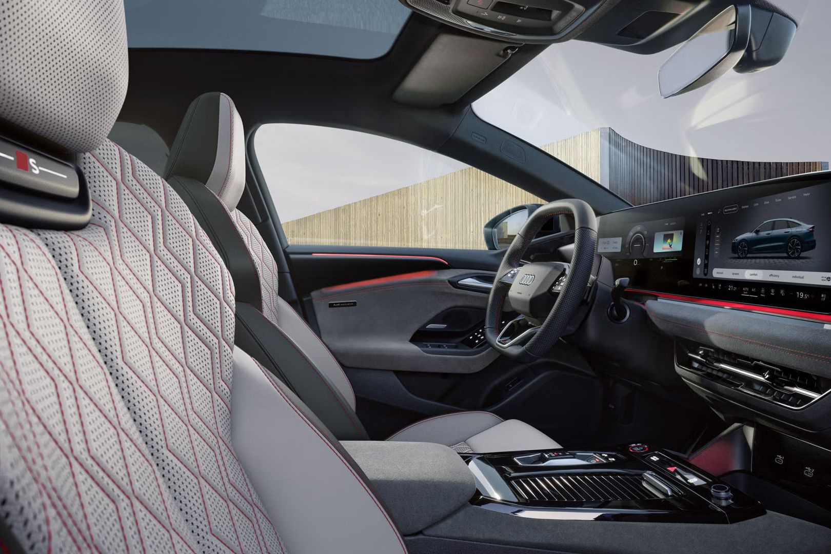 Blick von der Beifahrer-Seite in das Cockpit des S6 Sportback e-tron. Die Sitze haben Bezüge in Leder diamantsilver/jetgrau und Karmesinrote Kontrastnähte. Das Ambientelicht ist ebenfalls rot.