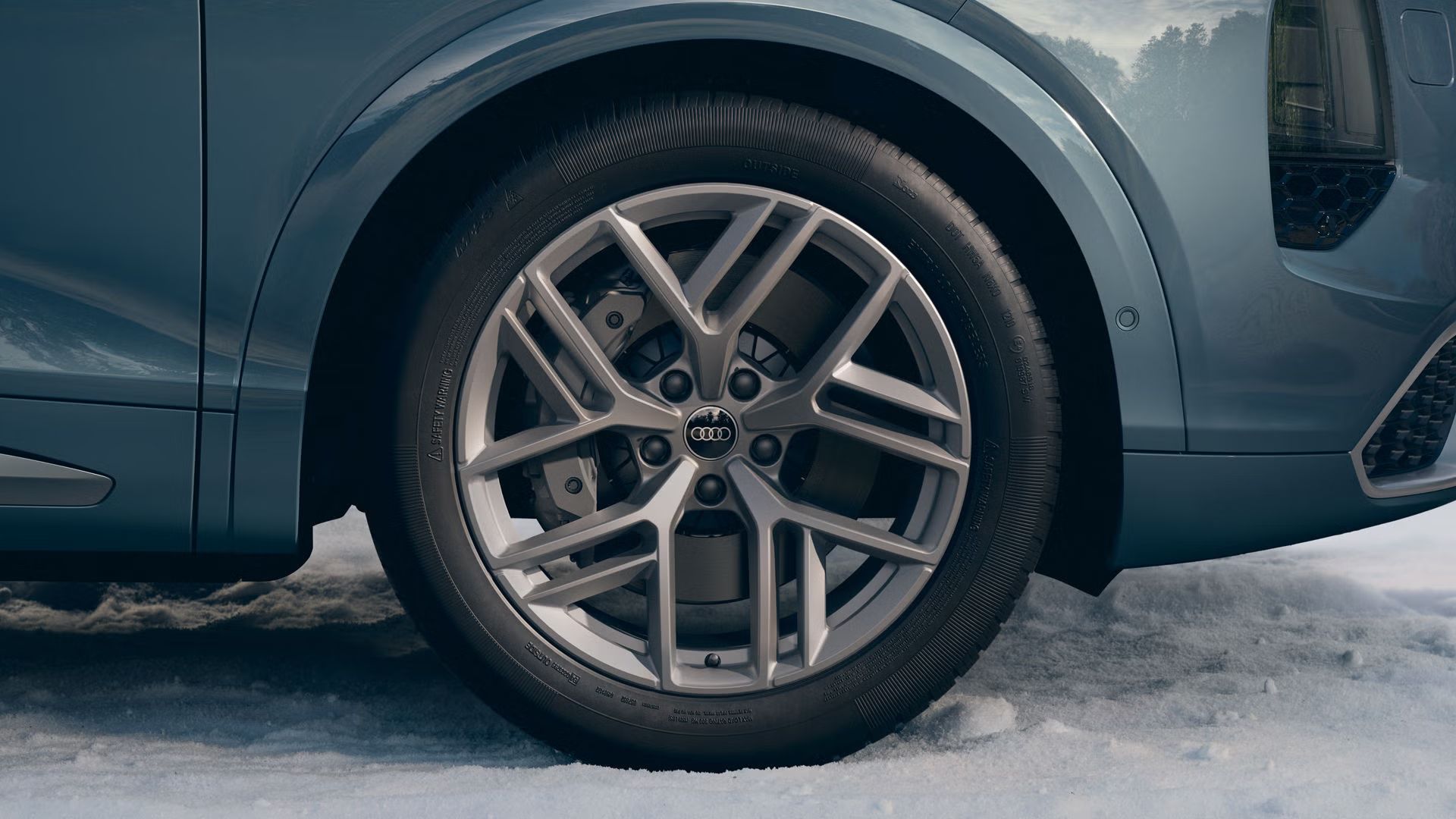 Detailný záber na koleso Audi s 21-palcovými diskami z ľahkej zliatiny v 5-lúčovom dizajne „Tripod“ v striebornosivej farbe.