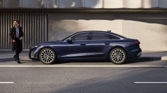  Modré Audi A5 Limuzína zaparkovaná pri chodníku vedľa modernej budovy.