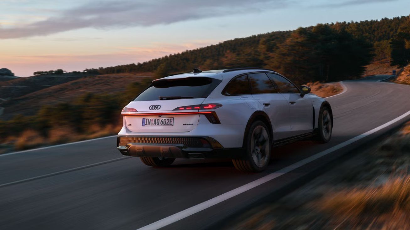 Audi A6 allroad e-hybrid zachytené z bočného pohľadu zo zadnej strany pri plnej rýchlosti na horskej ceste. V pozadí je les.