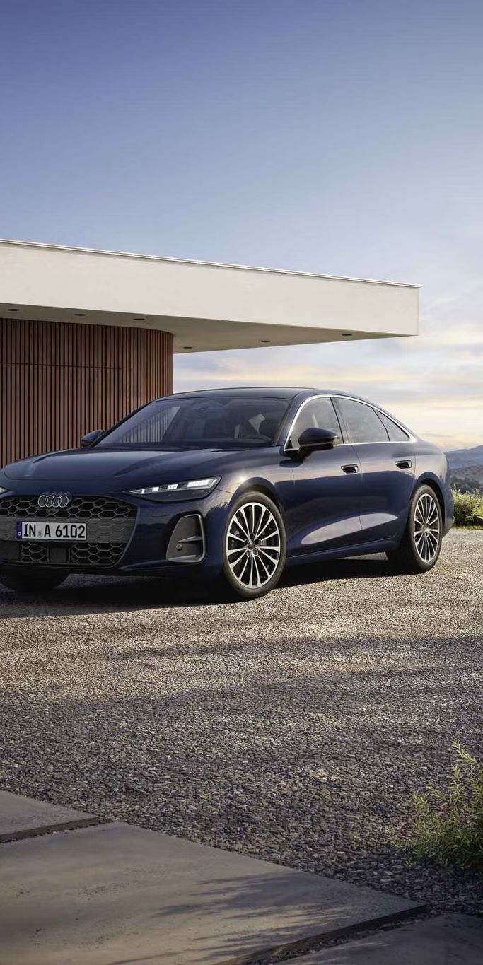 Die A6 Limousine steht im schrägen Frontprofil vor einem modernen Haus. 