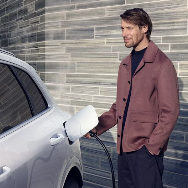 Muž pripája nabíjací kábel k Audi Q5 SUV e-hybrid.