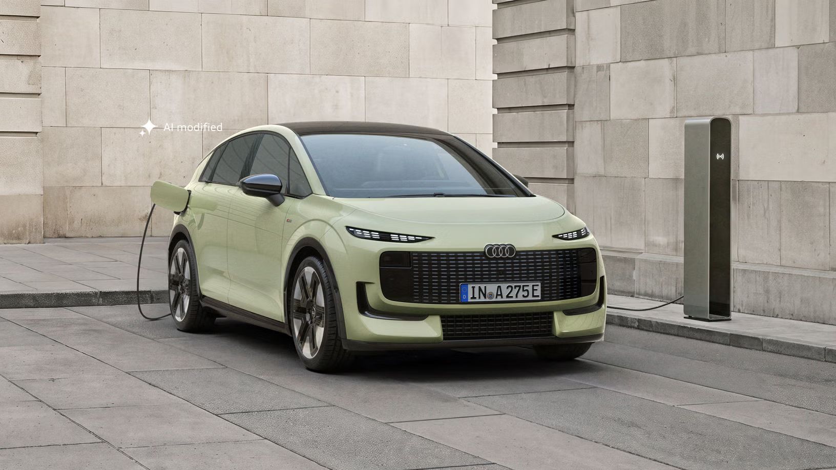 Audi A2 e-tron je zaparkované pred modernou budovou. Vozidlo je pripojené k nabíjacej stanici.
