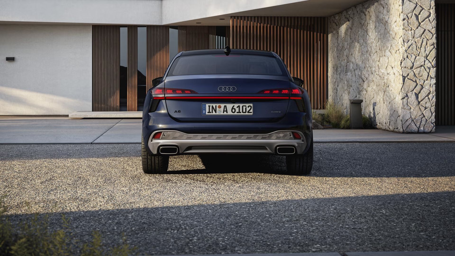 Pohľad na zadné partie Audi A6 Limuzína v pohľade zozadu. Vozidlo stojí pred moderným domom.