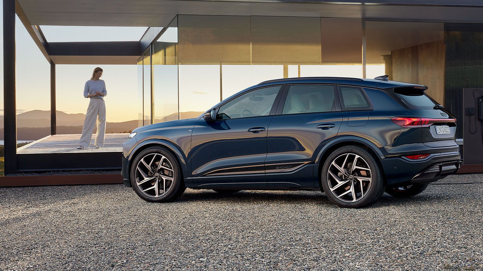 Audi Q6 SUV e-tron z bočného pohľadu pri modernom dome.