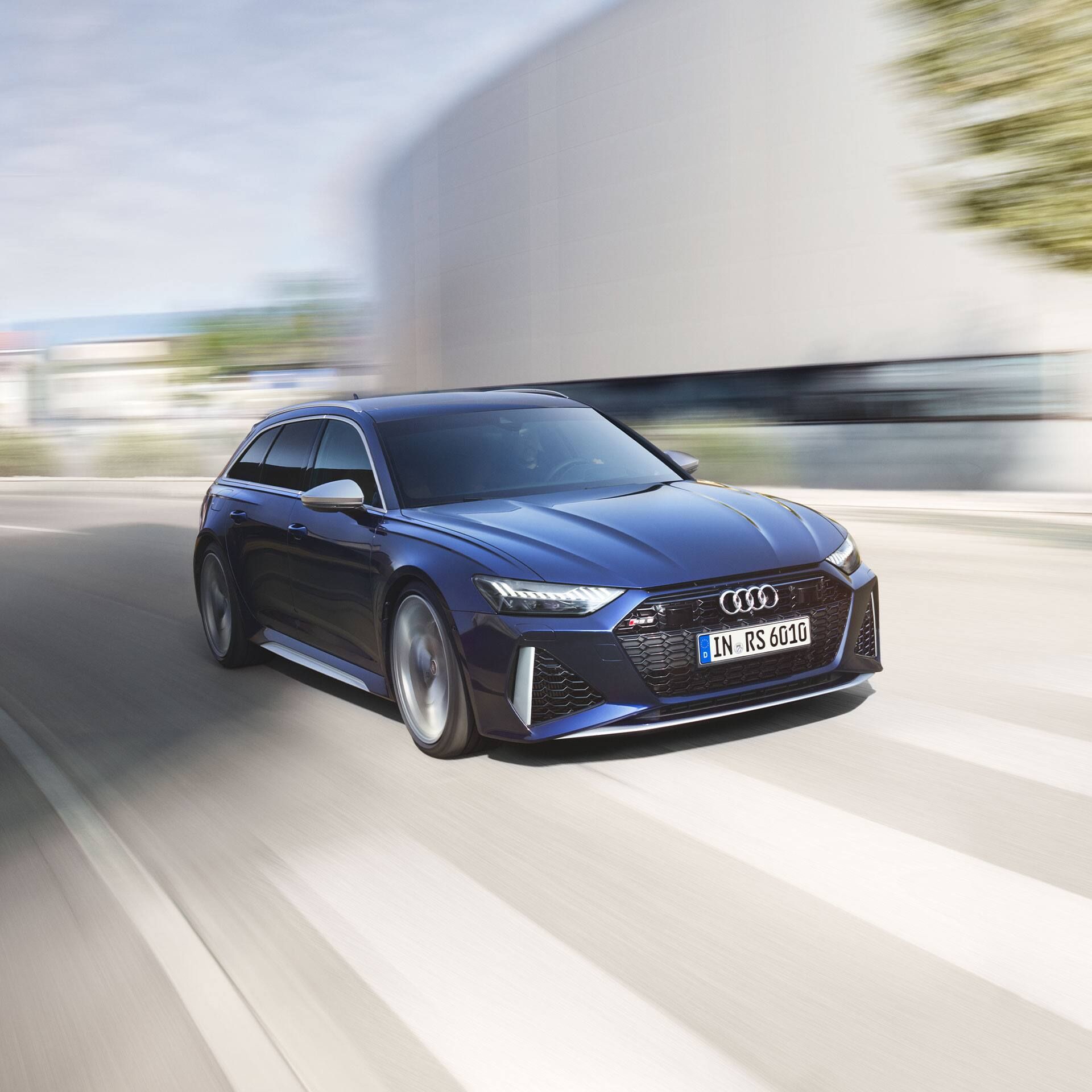 Modré Audi RS 6 Avant jazdí po ceste, zachytené pri rýchlej jazde. Pozadie je rozmazané kvôli rýchlosti vozidla.