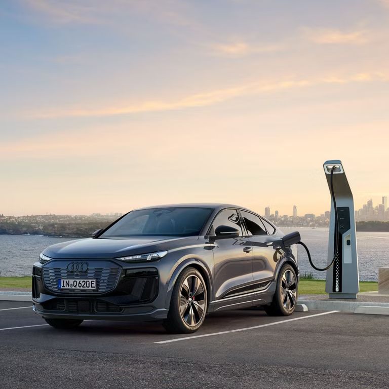 Bočný pohľad spredu na Audi Q6 pred nabíjacou stanicou