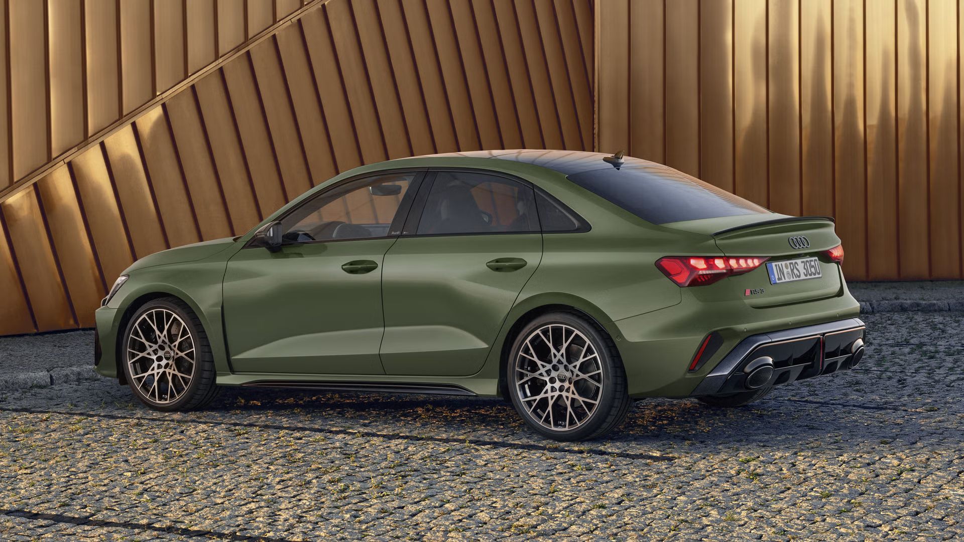 RS 3 Sportback s lakovaním s polárnym, matným efektom zaparkovaný zboku na dlažobných kockách, v pozadí obrysy modernej budovy.