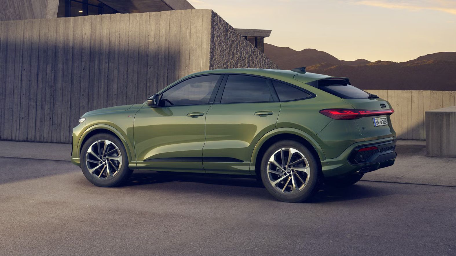 Zelené Audi Q5 Sportback z bočného pohľadu stojí na parkovisku pred vilou v horskom prostredí.