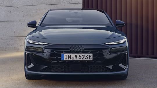 Pohľad na Audi A6 Sportback e-tron spredu, ktoré parkuje pred budovou.