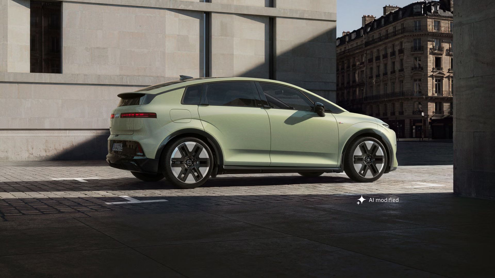 Audi A2 e-tron, odfotené z boku, je zaparkované pred modernou budovou v meste. Slnečné svetlo vytvára scenériu s tieňmi. 