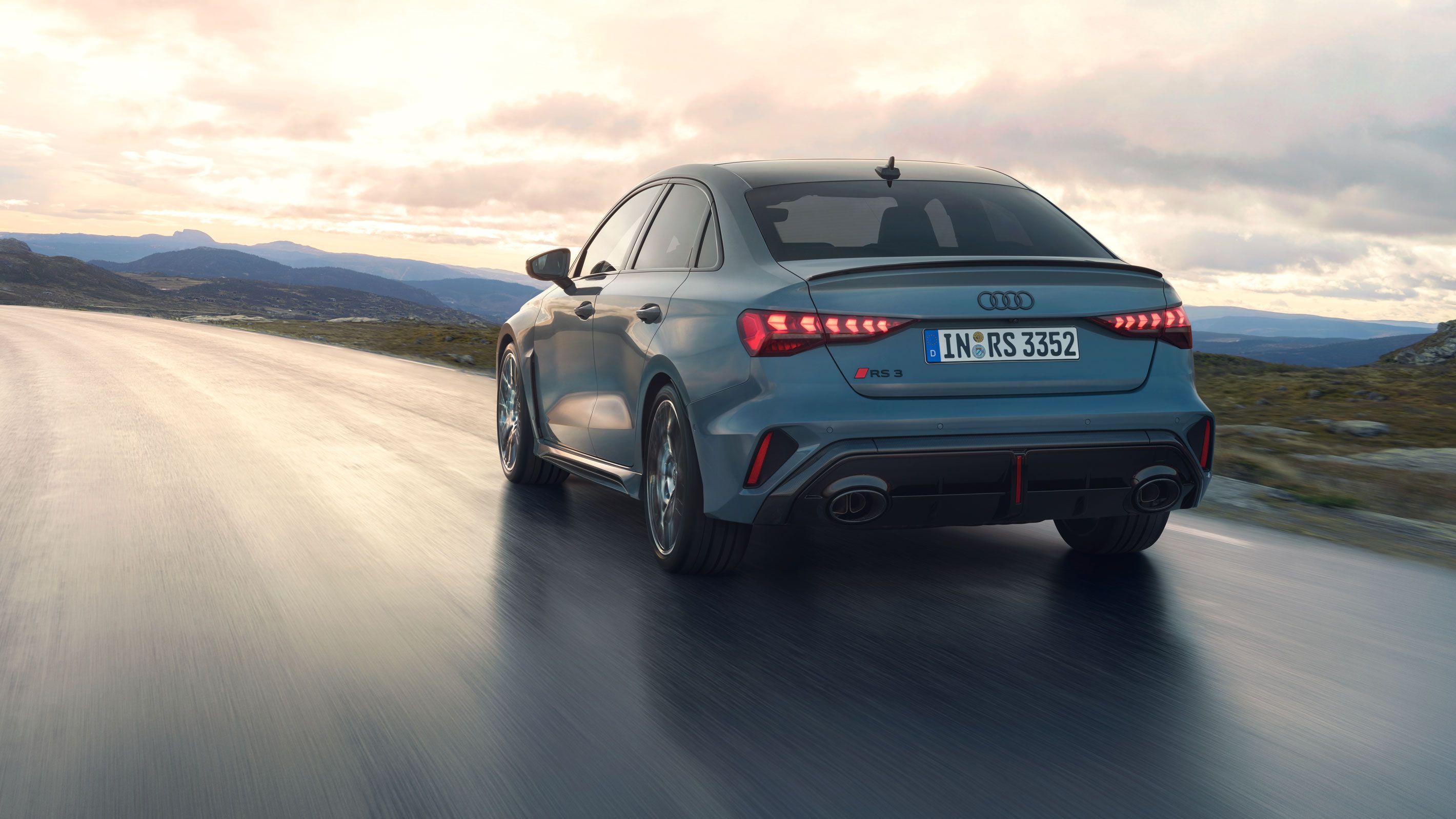 Pohľad na zadné partie Audi RS 3 Limuzína počas dynamickej jazdy na ceste v horách.