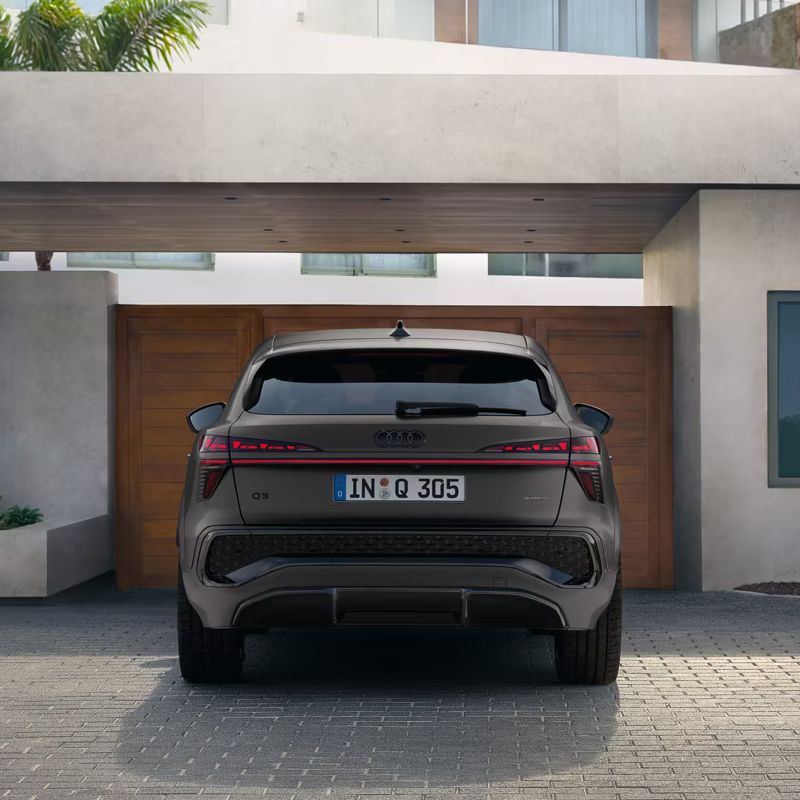Audi Q3 Sportback zaparkované pred modernou vilou z prémiových materiálov.
