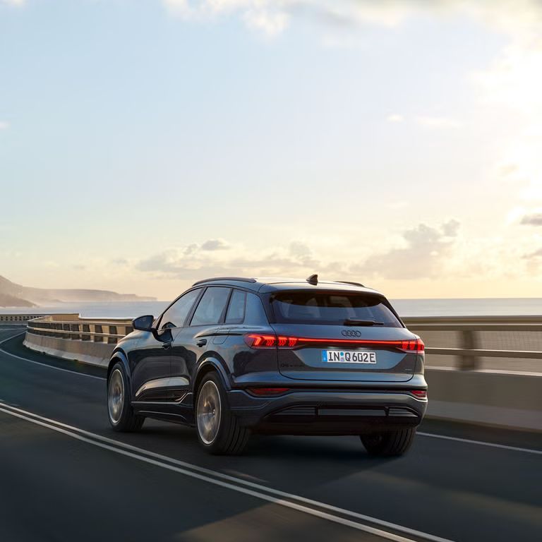 Audi Q6 SUV e-tron počas jazdy na moste v zálive.