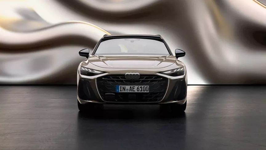 Audi A6 Avant spredu stojí pred zaujímavou zvlnenou stenou v svetlo hnedom odtieni.