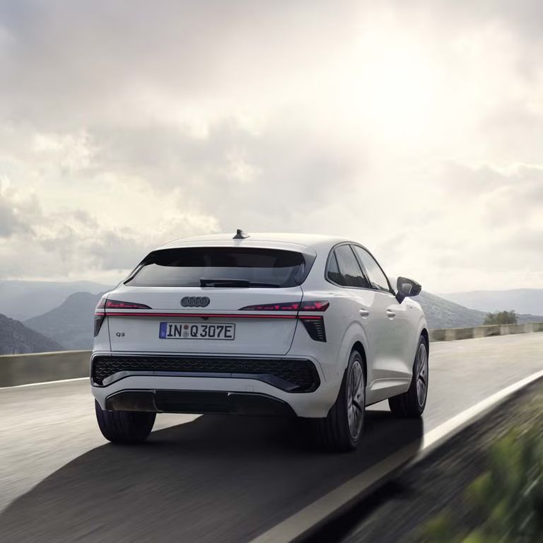 Biely Q3 Sportback e-hybrid ide po ceste v horskej krajine.	